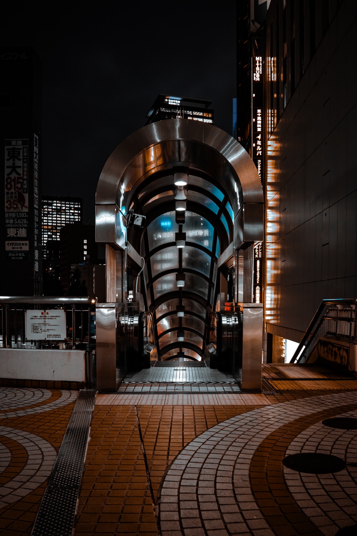 A lit tunnel entrance and surrounding city signs at night.