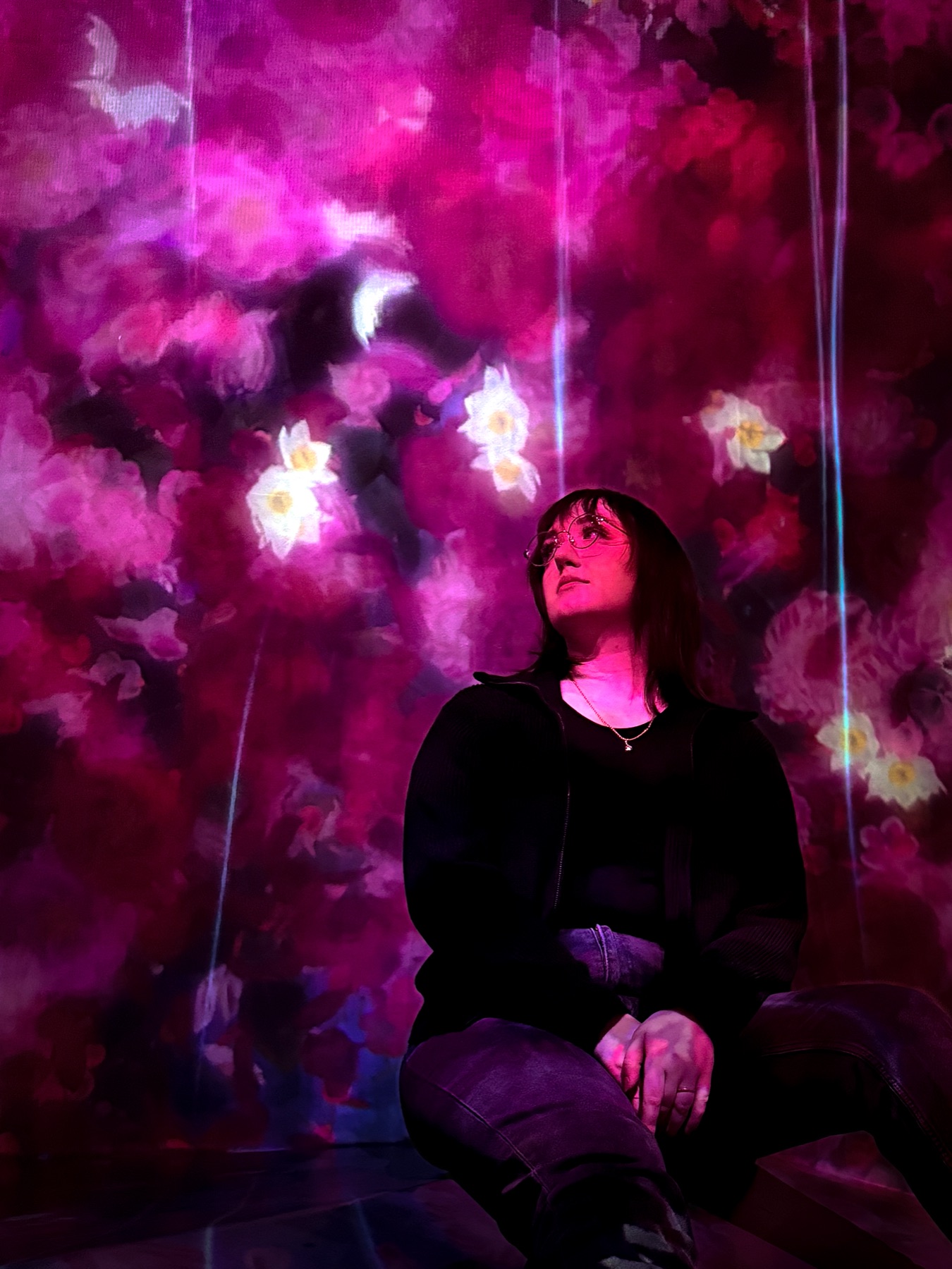 A portrait inside a vivid pink floral light installation.