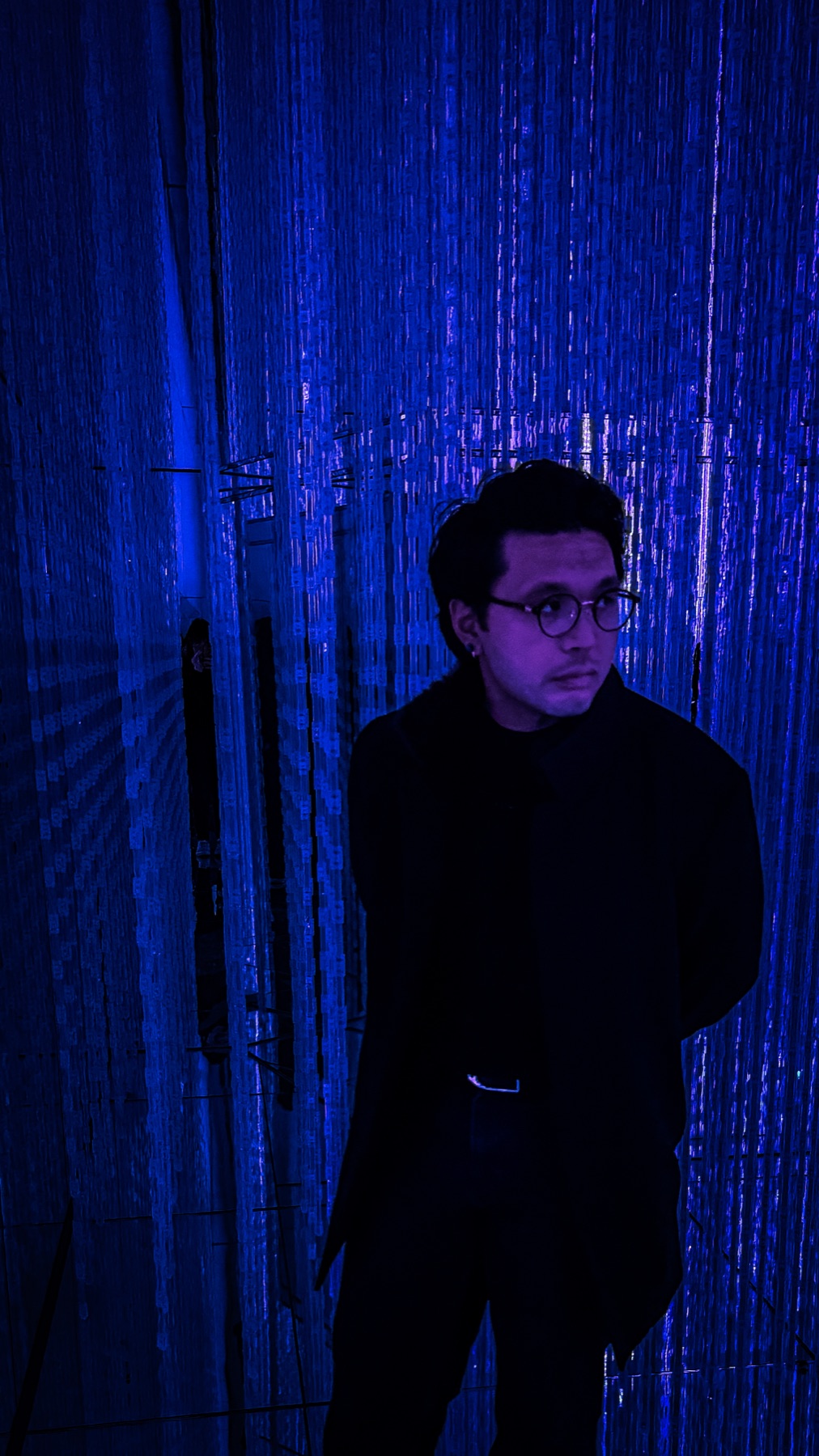 Christopher Abarca standing inside a blue-lit installation space.
