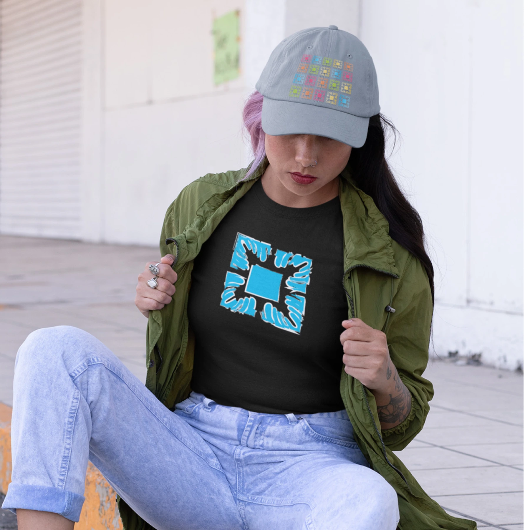 Seated model wearing a black Manoa Now shirt with a bright quilt-inspired mark.
