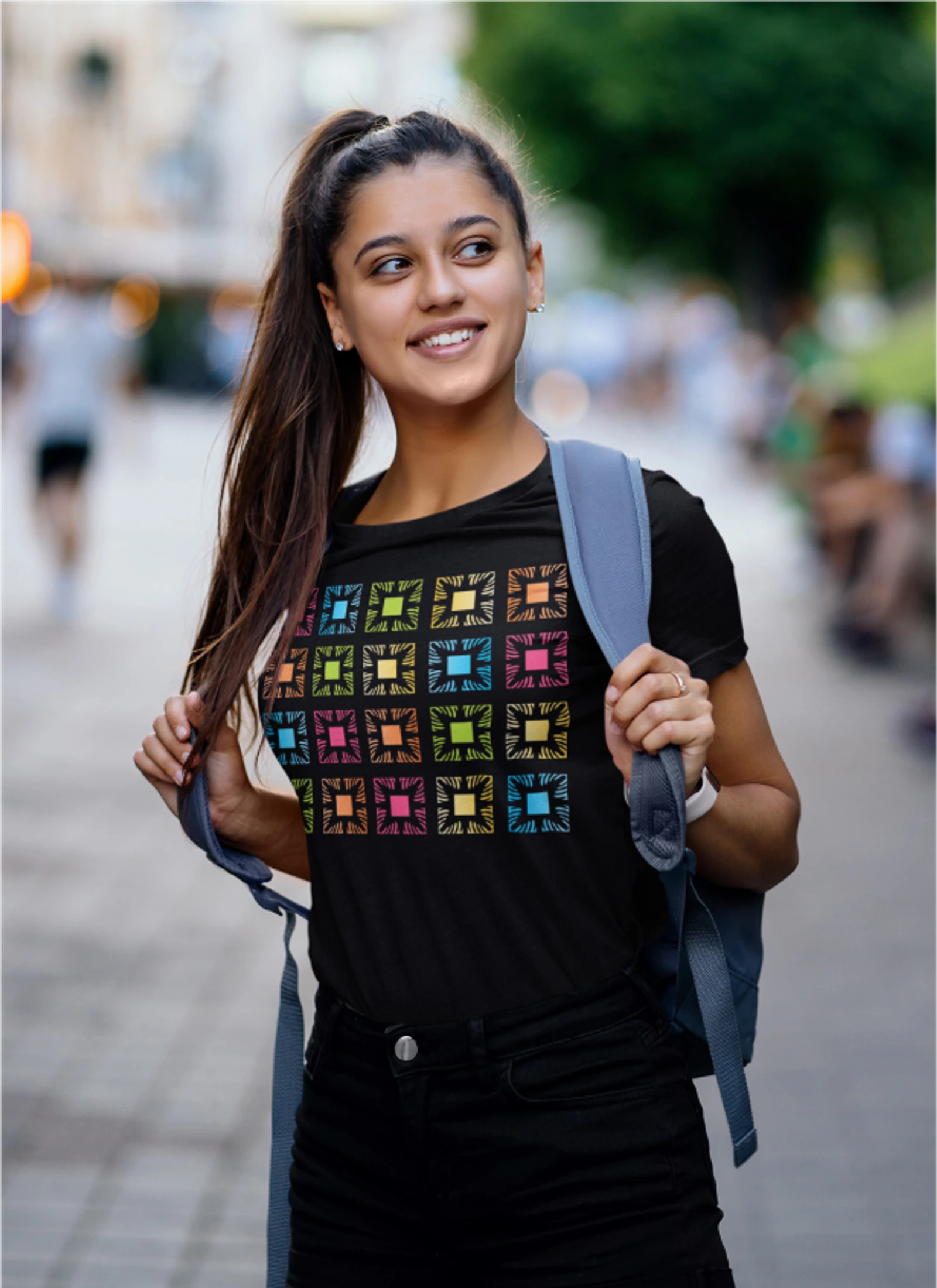 Model wearing a black Manoa Now shirt with a multicolor icon grid.