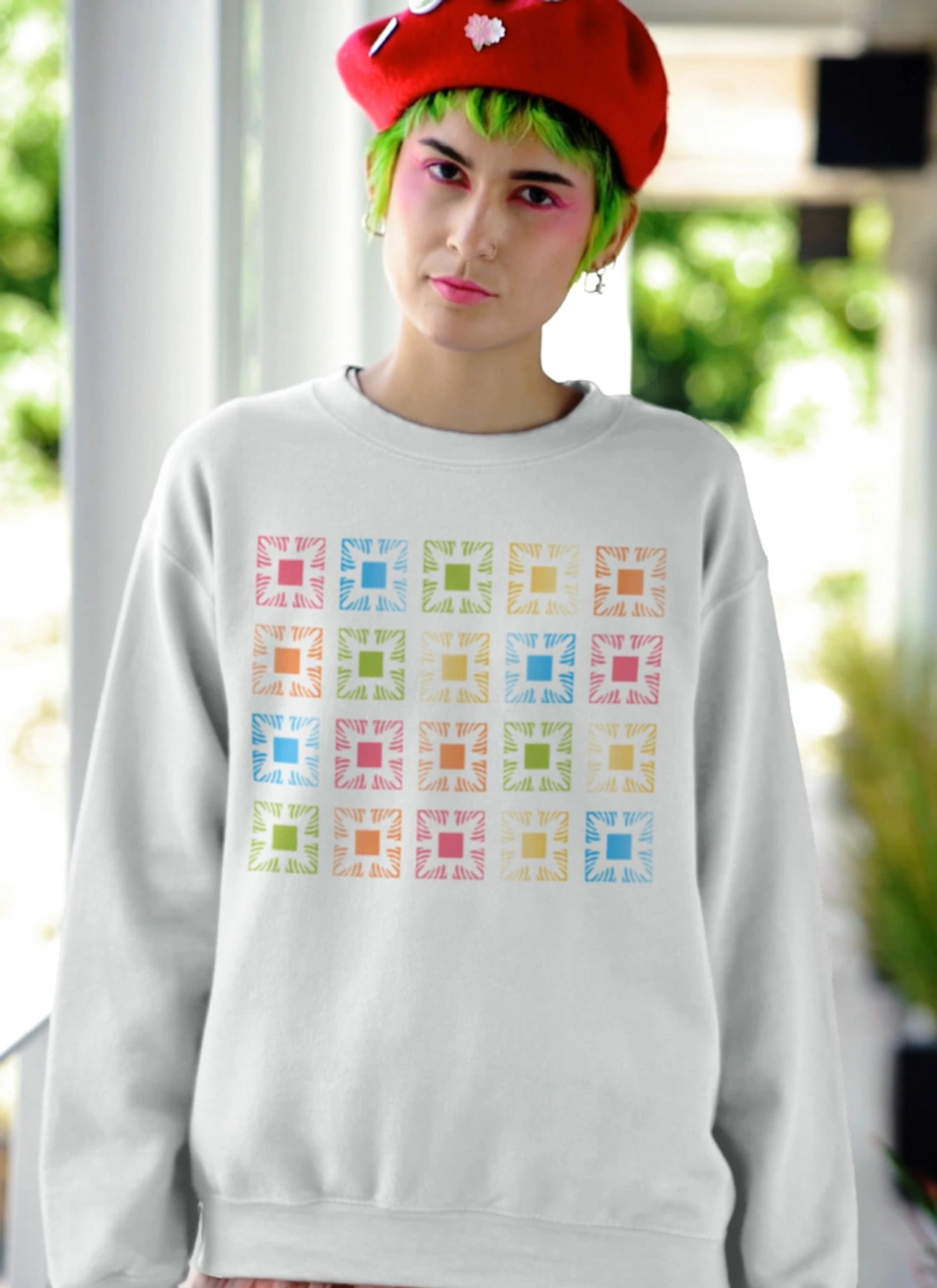 Model wearing a cream Manoa Now sweatshirt with colorful square graphics.