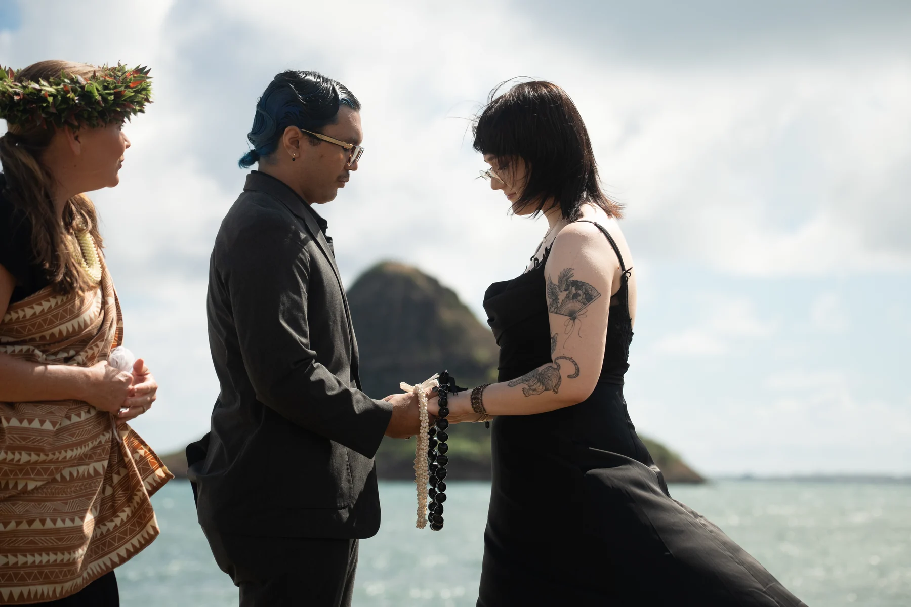 A couple holding hands during an outdoor beach ceremony.