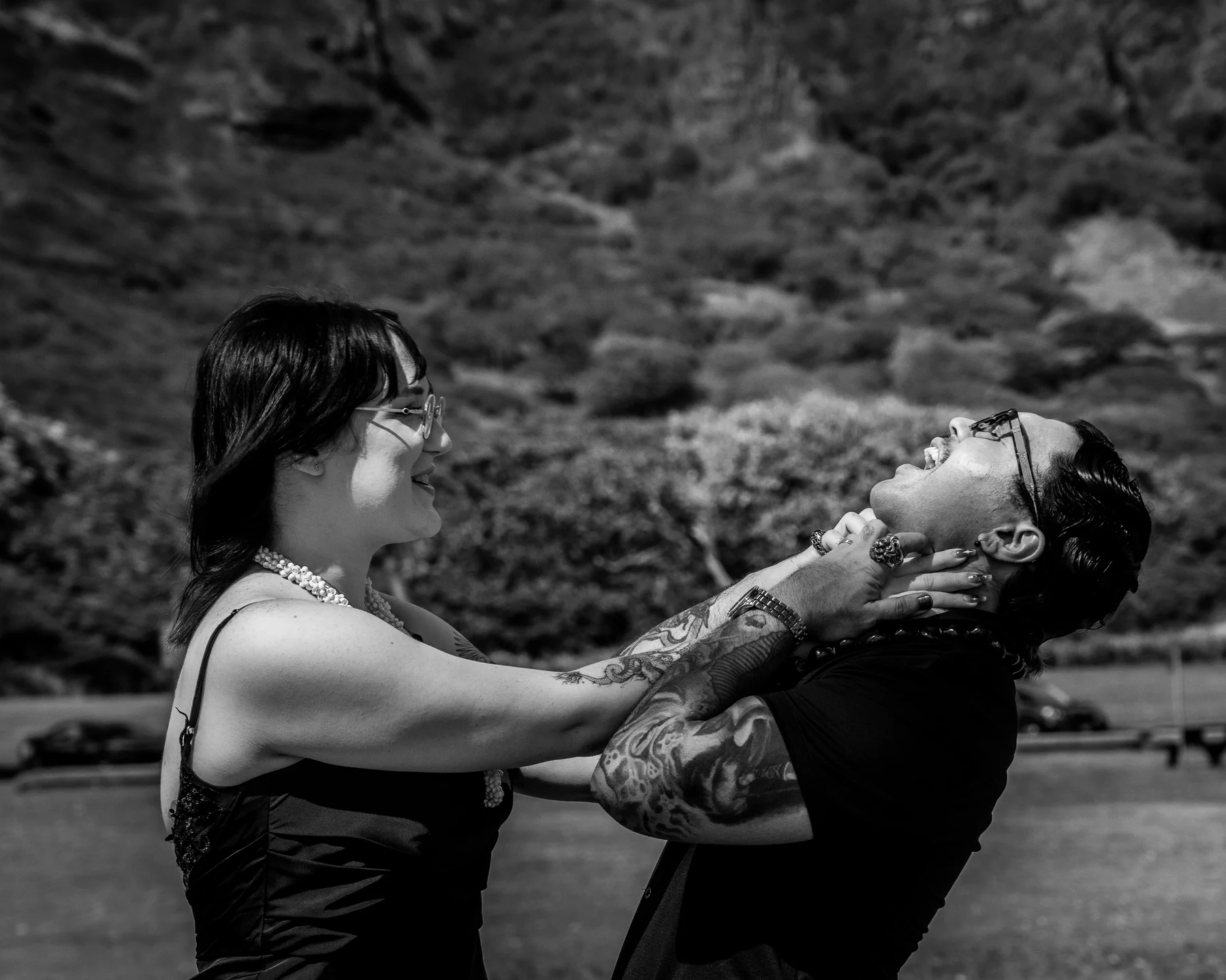 A playful black-and-white portrait of a couple outdoors.