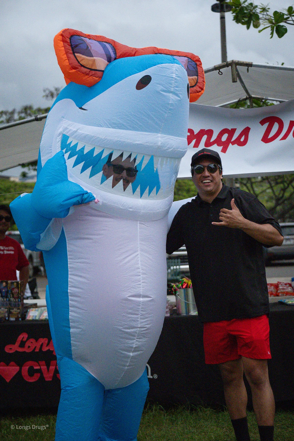 A smiling attendee posing beside a playful inflatable shark.