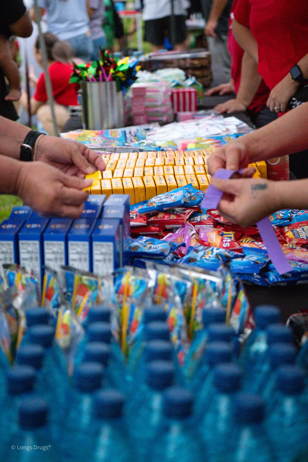 Hands reaching across a colorful community giveaway table.