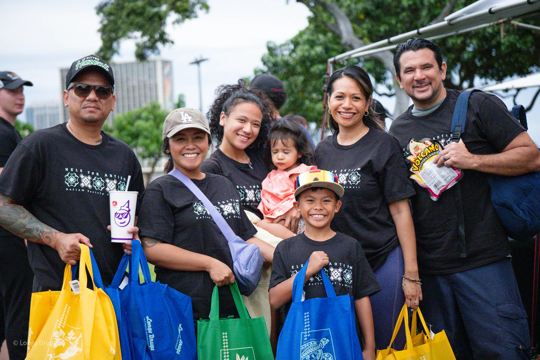 A family smiling together while holding colorful event bags.