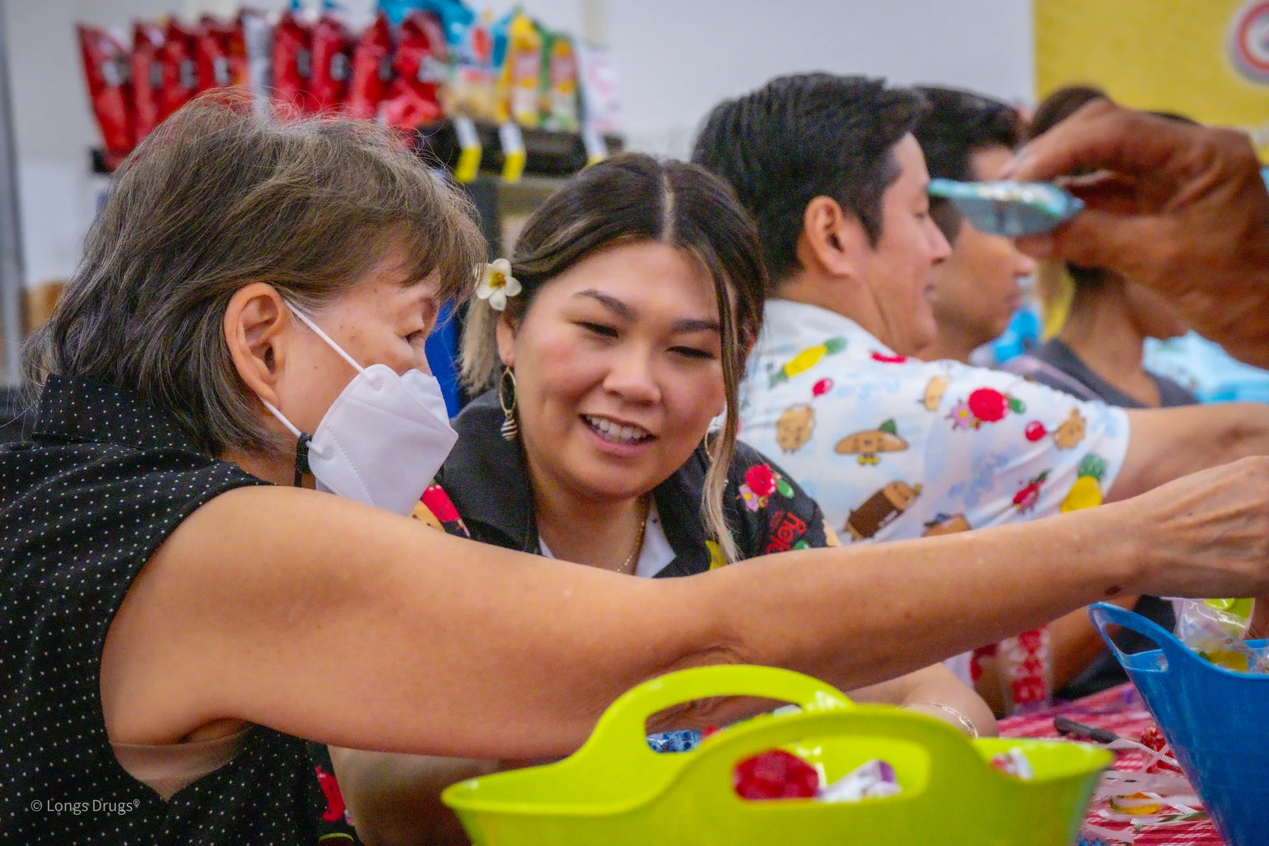 Two people smiling while working together at a Lei Day craft table.