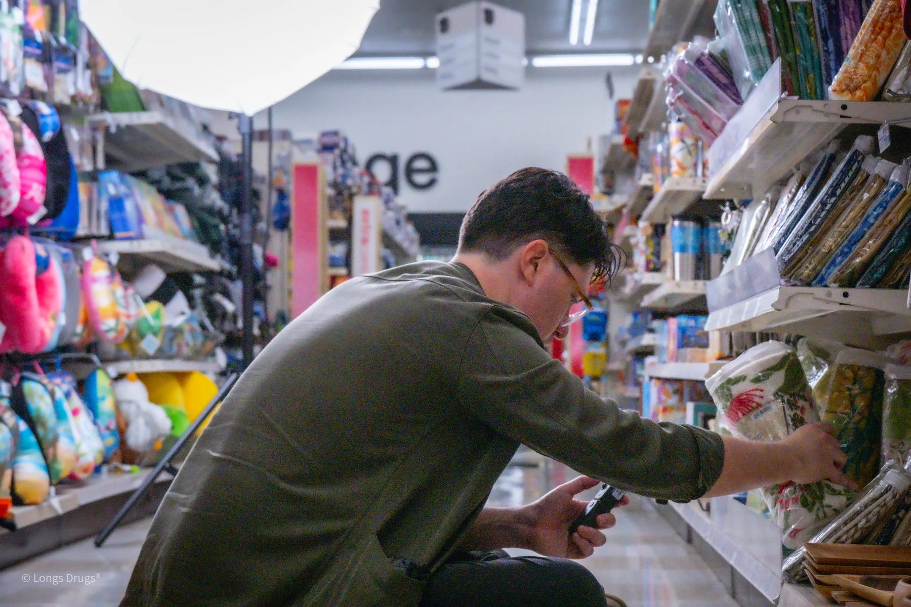 A videographer selecting materials from a colorful store shelf.