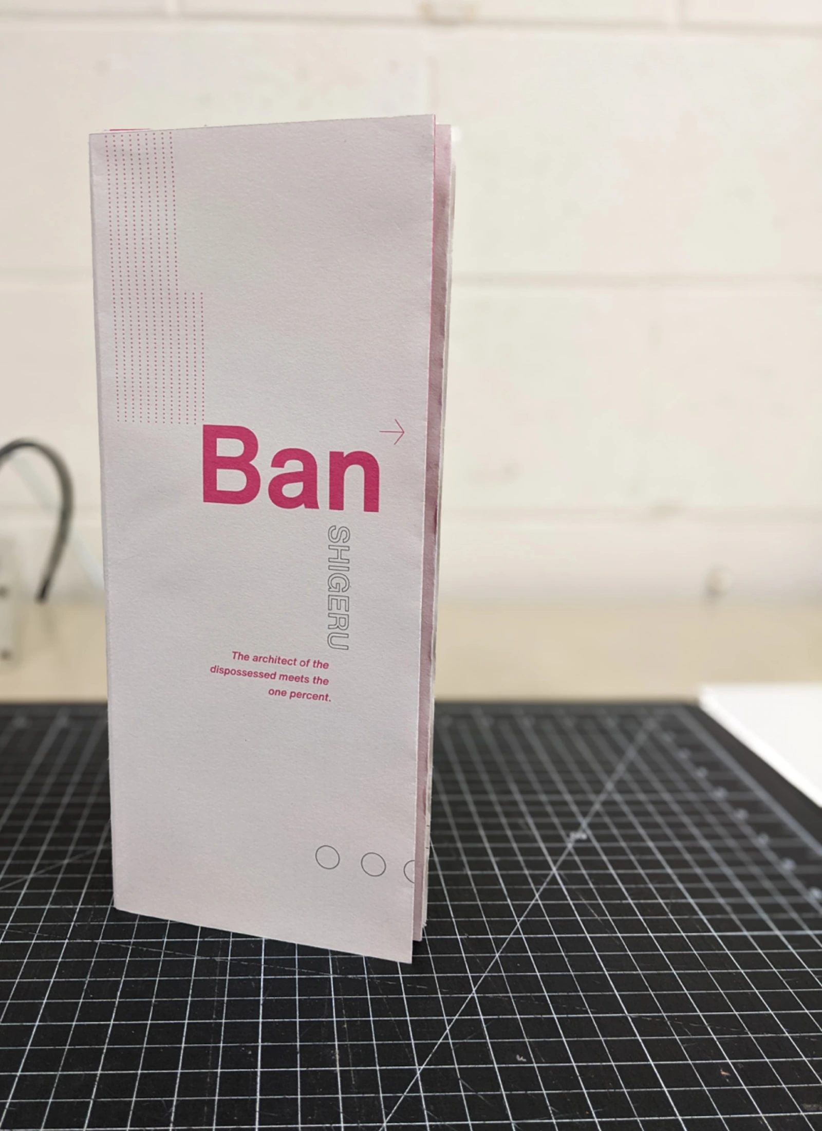 Vertical folded booklet marked Ban standing on a cutting mat.